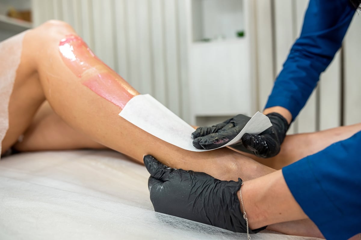 Female client legs applying pasta for depilation, the procedure of removal unwanted hair in spa
