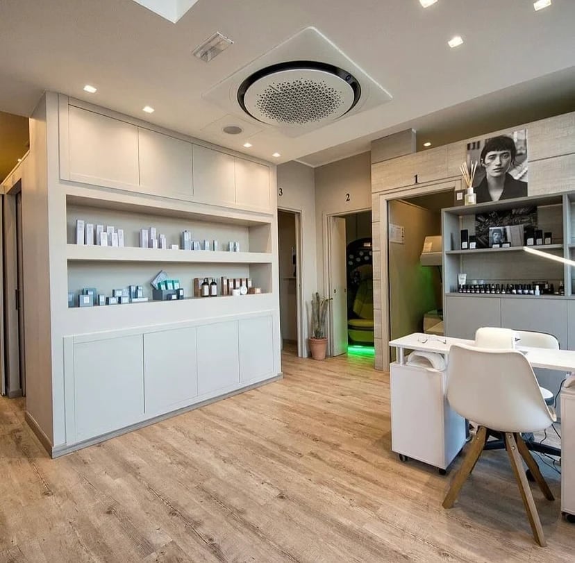 Modern salon interior with white cabinetry, product shelves, wooden flooring, and a consultation area with seating